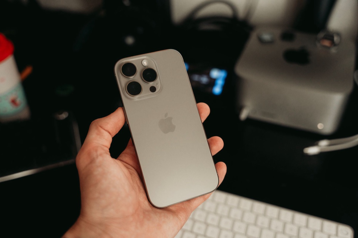 junge australische you-tuber mit laptop und smartphone in minimalistischem studio